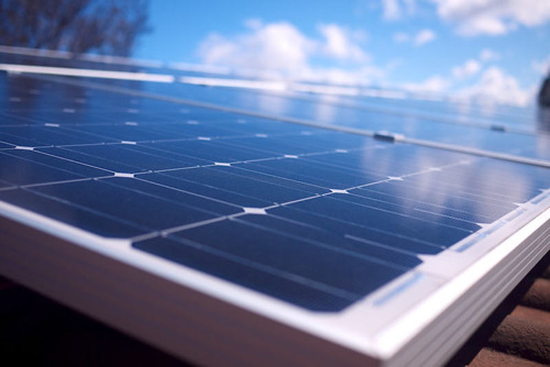 Placas solares instaladas en un tejado y de fondo un cielo azul con nubes.